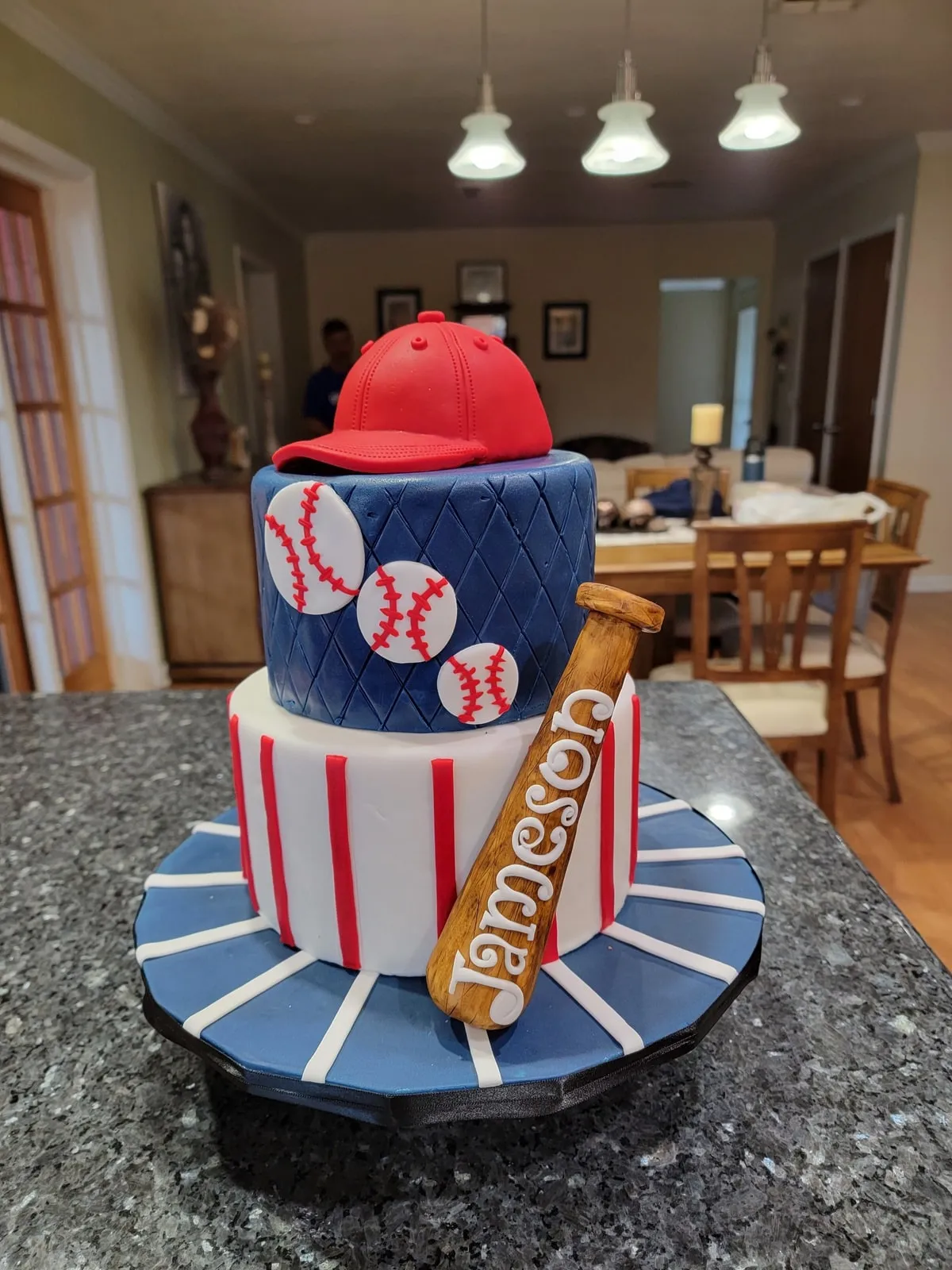 Baseball themed cake with sculpted cap, bat and ball on a pinstripe tier