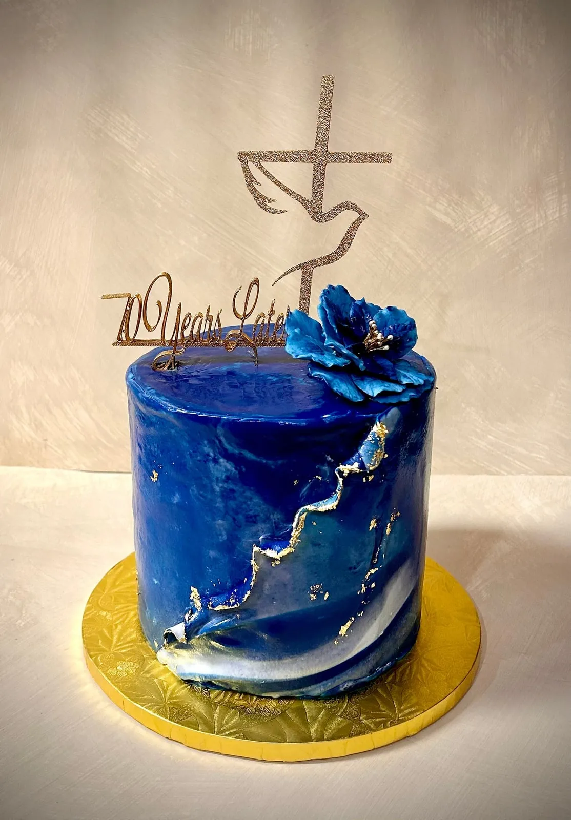 Deep blue geode cake with gold leaf edging and a sugar flower