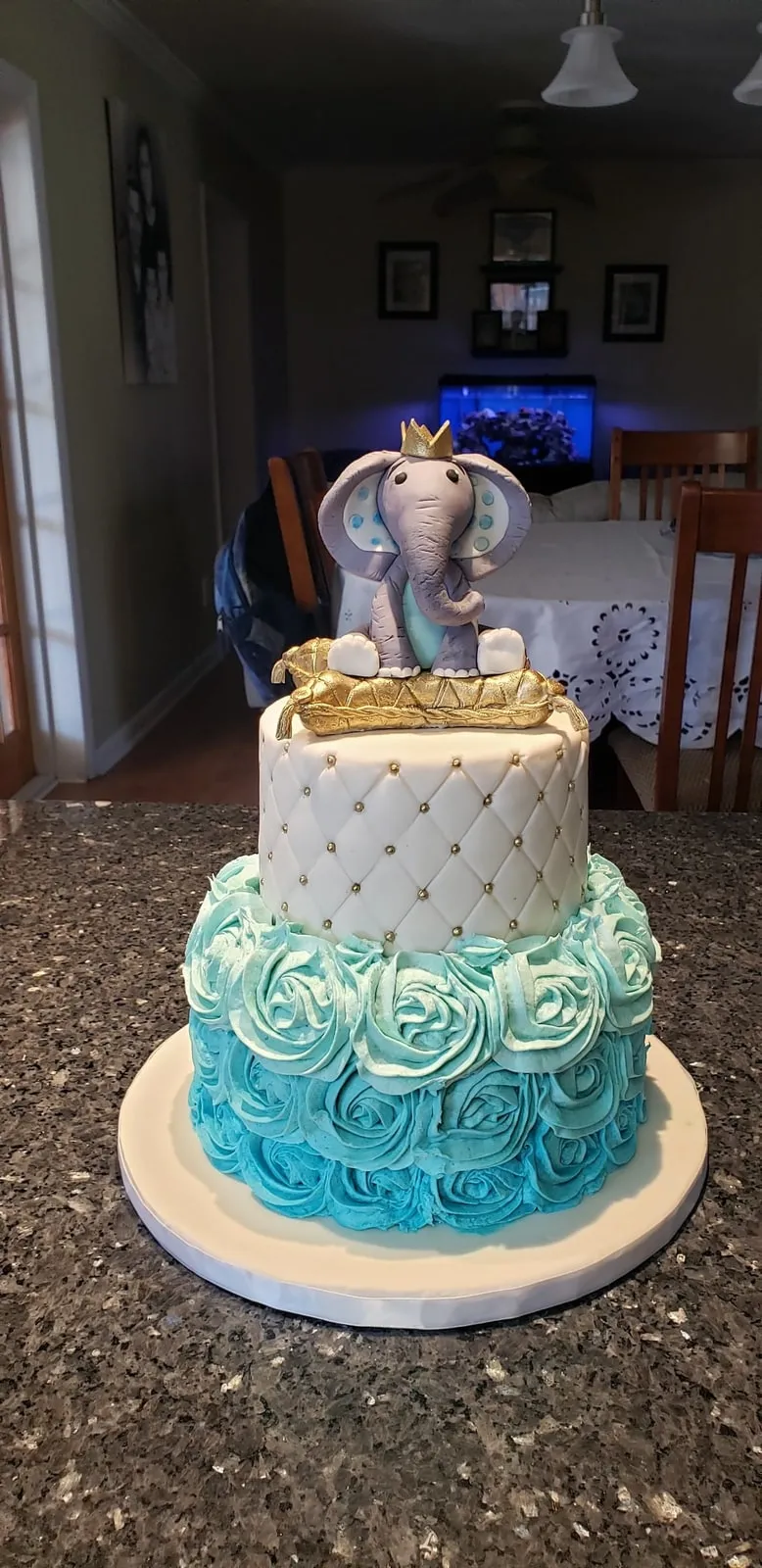 Two tier baby shower cake with blue buttercream rosettes and a sugar elephant
