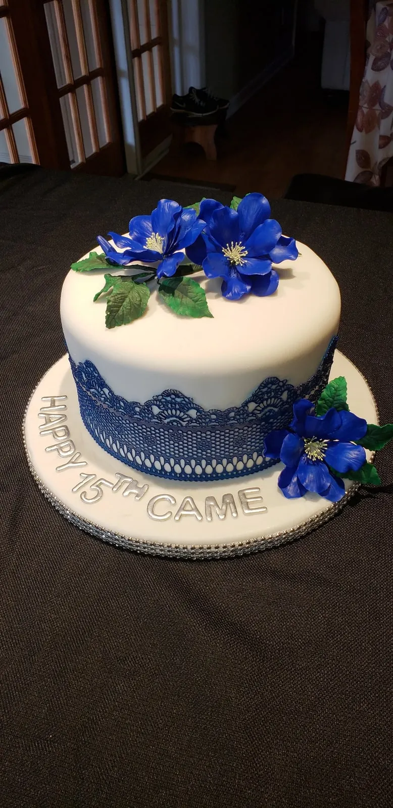 White fondant quinceañera cake with blue sugar flowers, blue lace detail and Happy 15th lettering