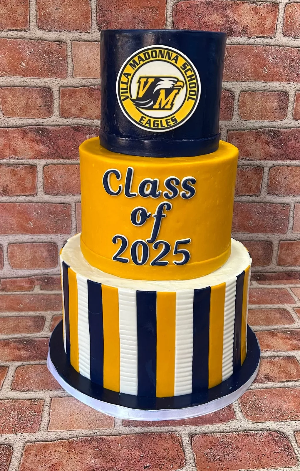 Three tier Class of 2025 graduation cake in navy and gold stripes