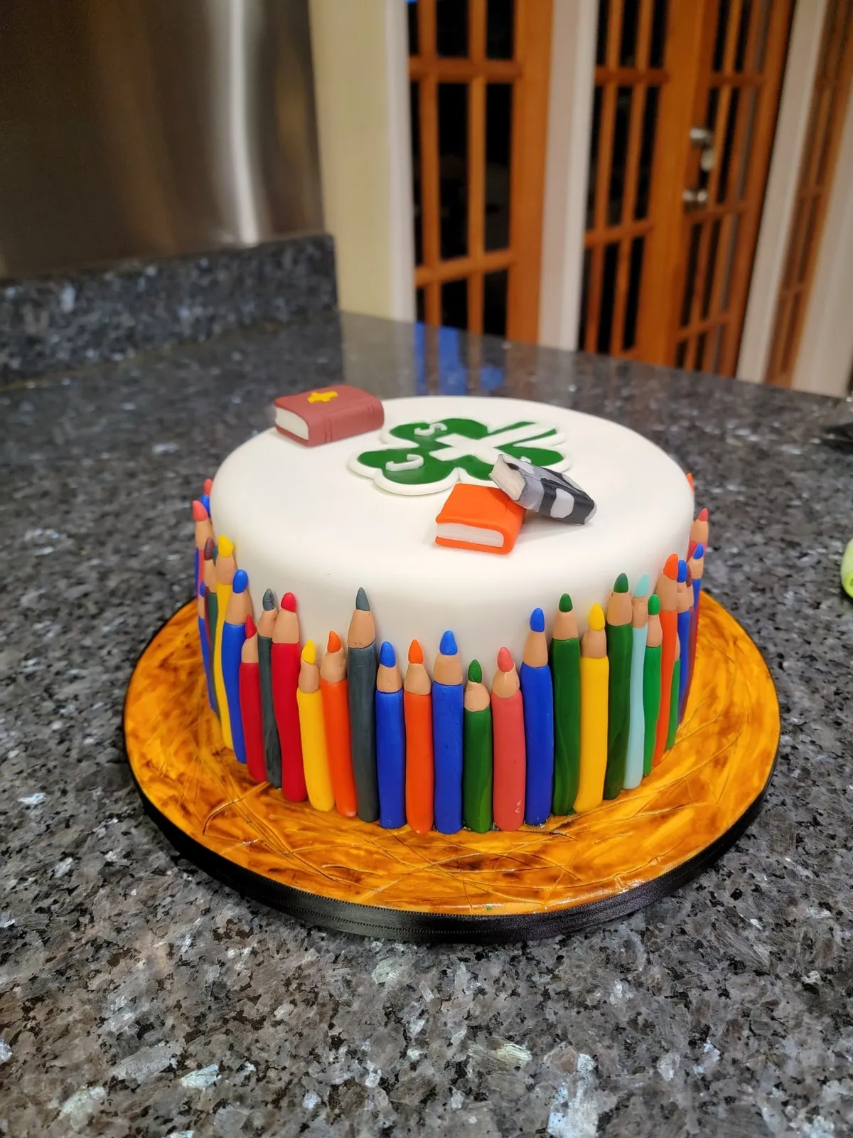 Teacher cake ringed with fondant coloured pencils and school supplies
