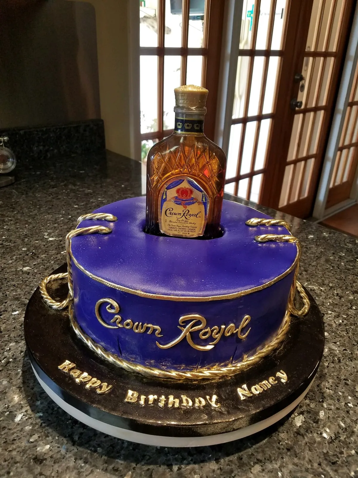 Sculpted Crown Royal bottle birthday cake in purple and gold fondant