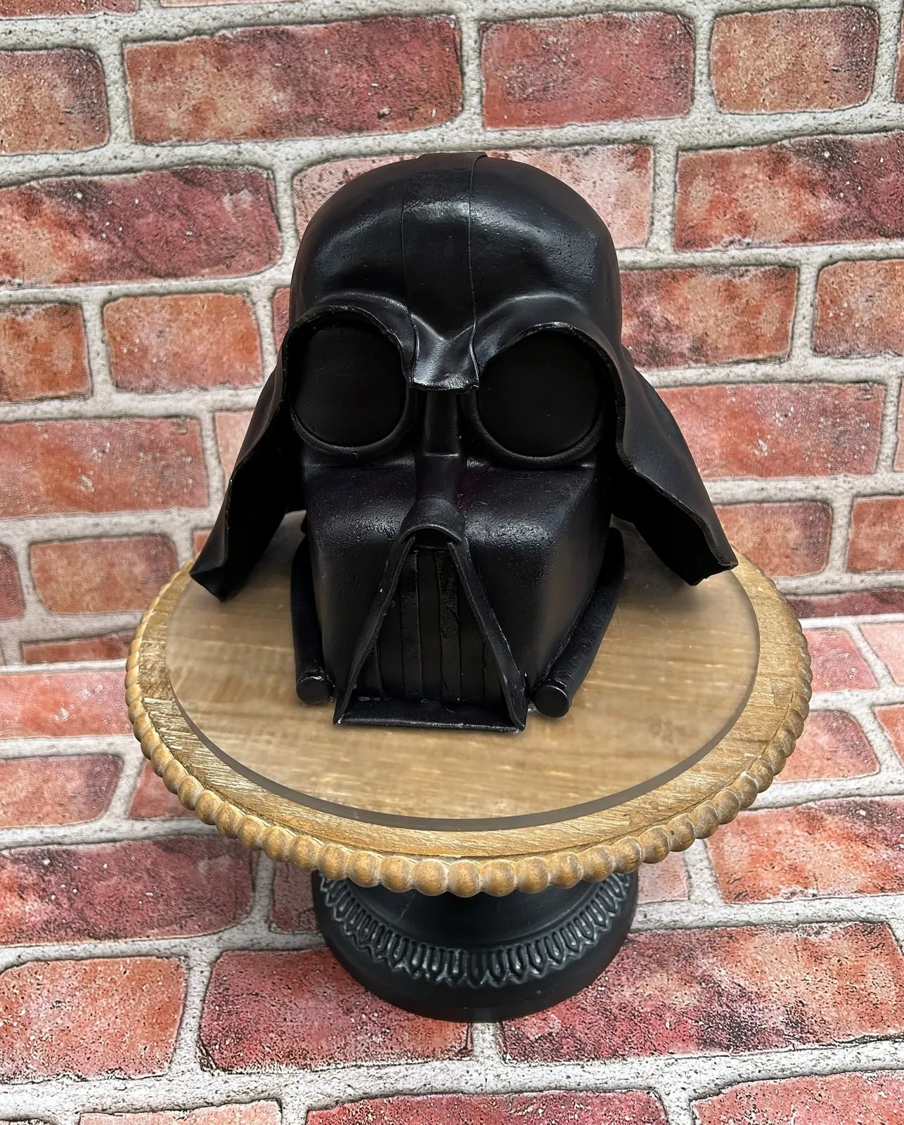 Sculpted Darth Vader helmet cake in black fondant on a wood stand