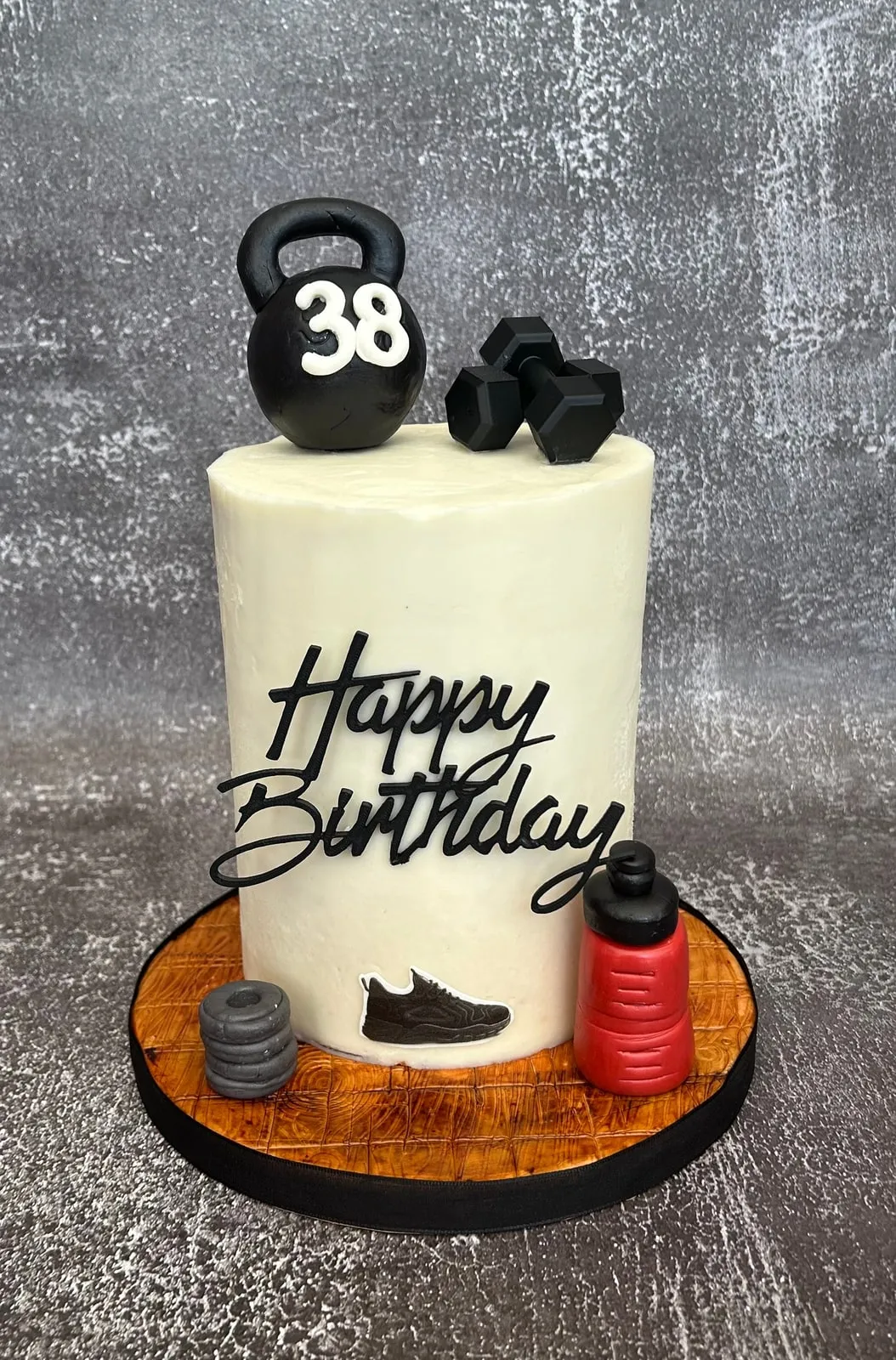 Fitness themed birthday cake with sculpted kettlebell, dumbbells and trainers