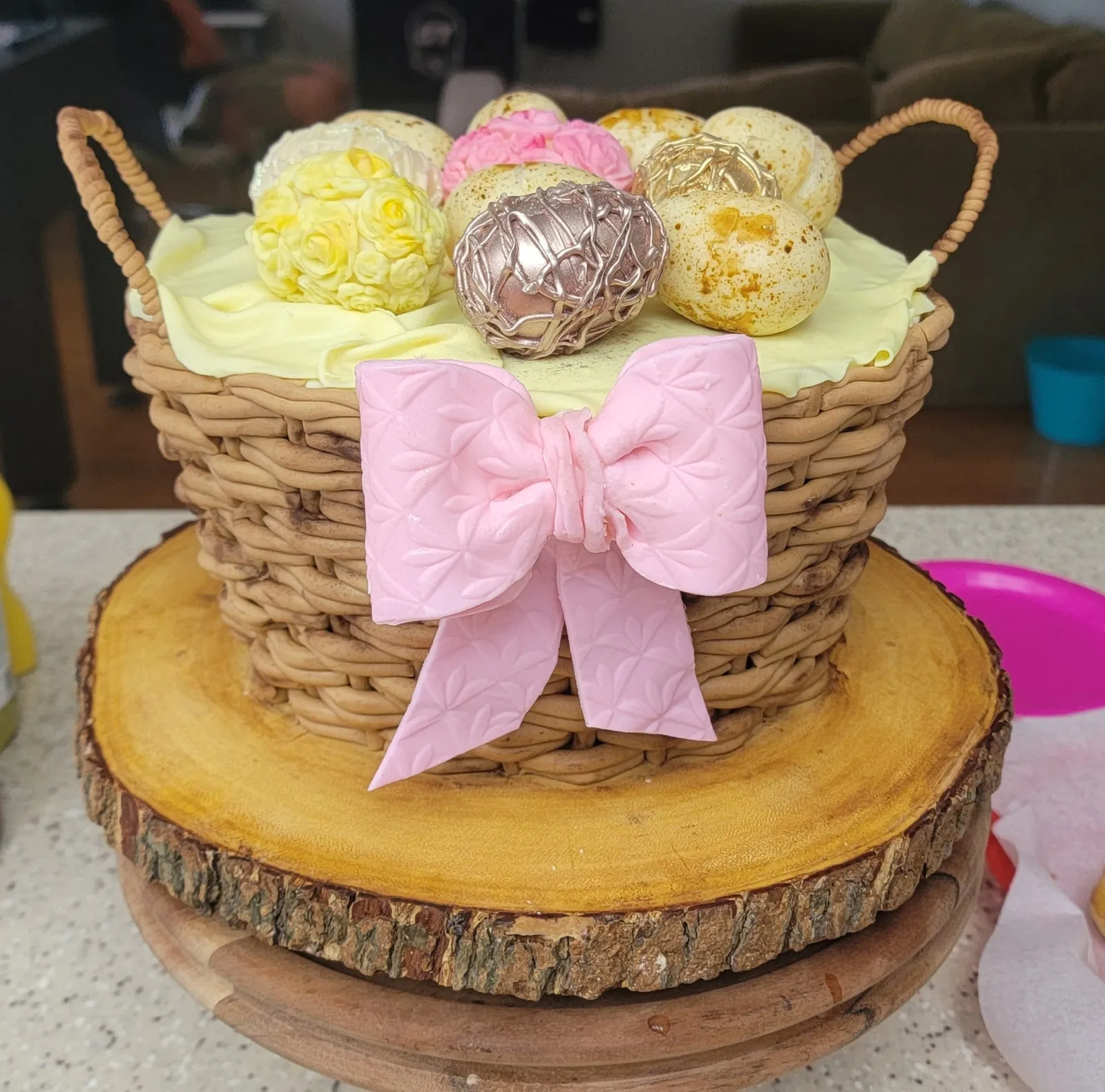 Baby shower cake sculpted as a woven basket of buttercream flowers with a pink bow