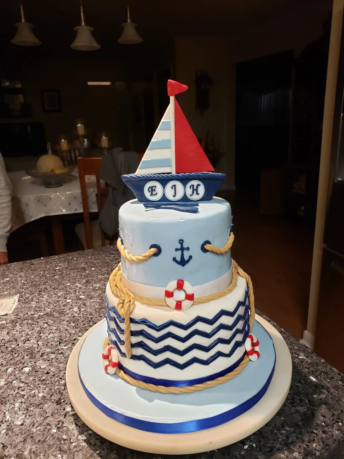 Nautical two tier baby shower cake with anchor, chevron stripes and a sailboat topper