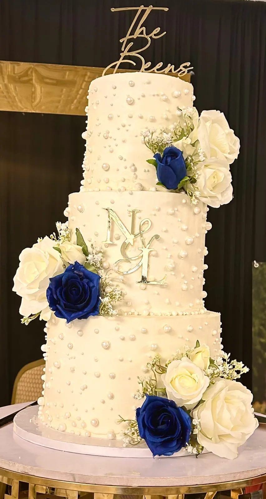 Four tier ivory wedding cake with textured buttercream and navy and white sugar roses