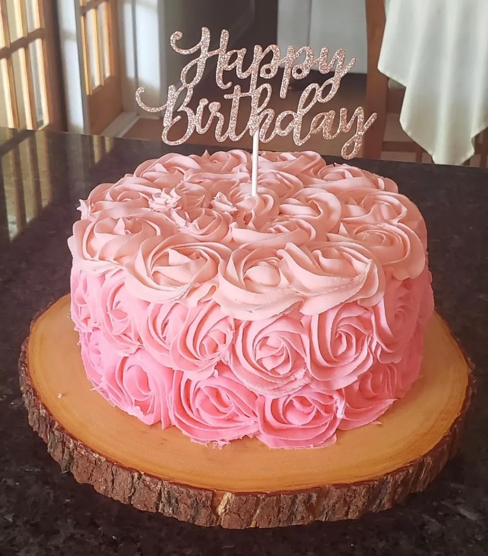 Pink buttercream rosette birthday cake on a wood slice stand