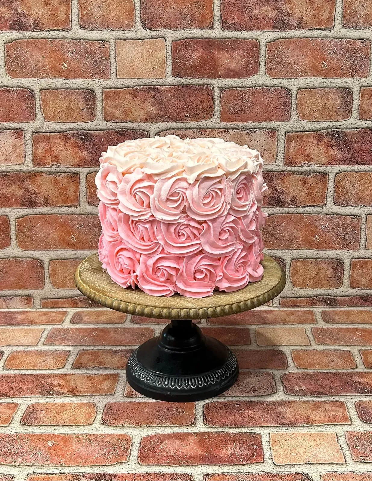 Tall pink buttercream rosette cake on a black pedestal stand
