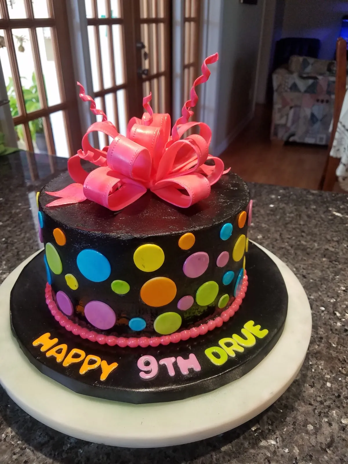 Black birthday cake with bright polka dots and a large pink fondant bow