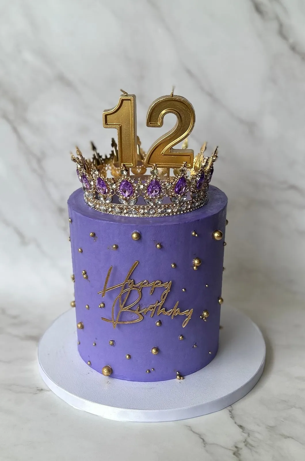 Lavender birthday cake with gold dragees and a jewelled crown topper