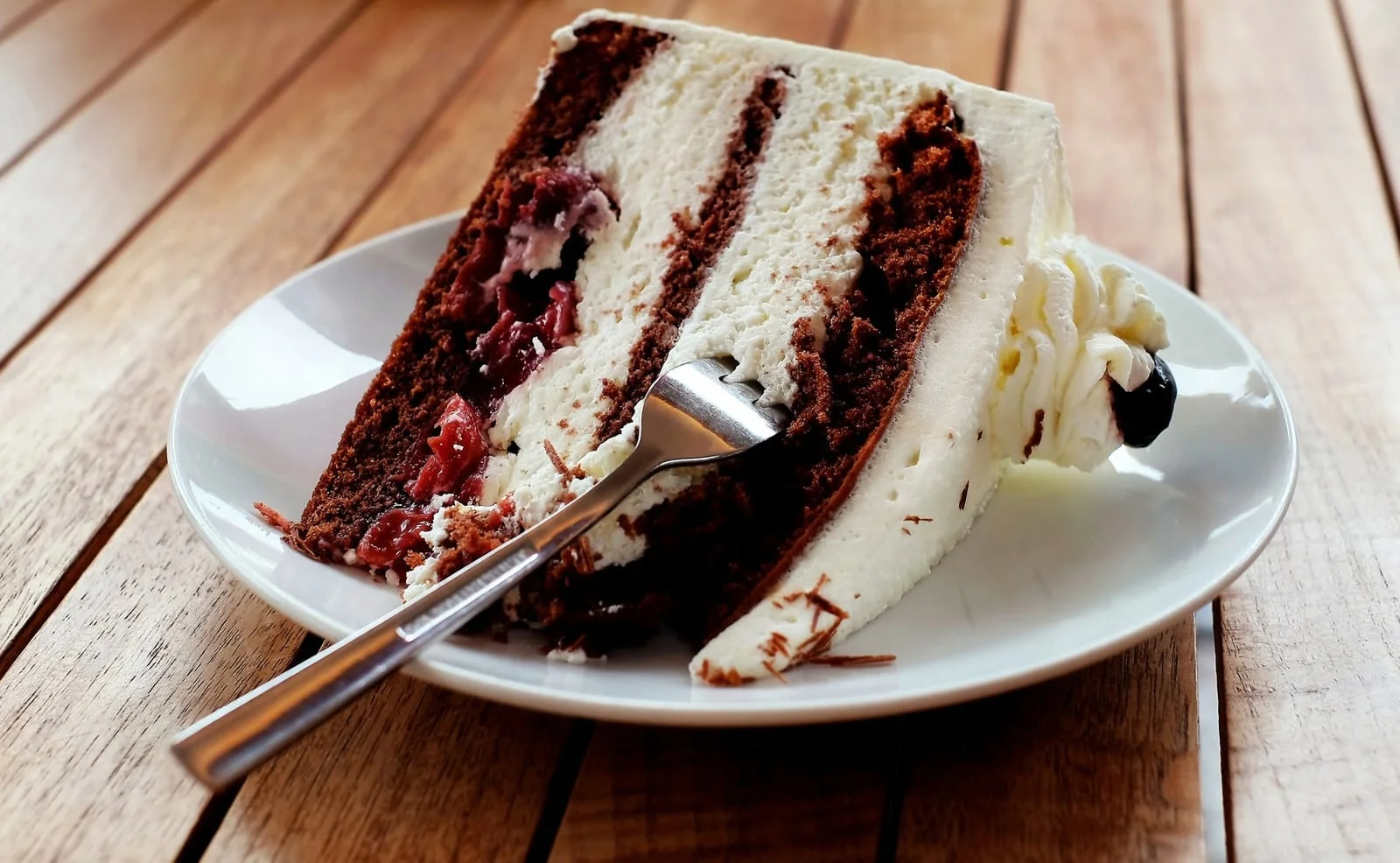 Slice of layered red velvet cake with cream cheese filling on a white plate
