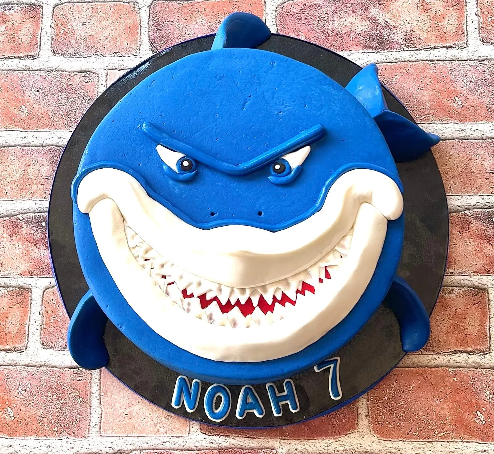 Sculpted blue shark birthday cake with detailed fondant teeth