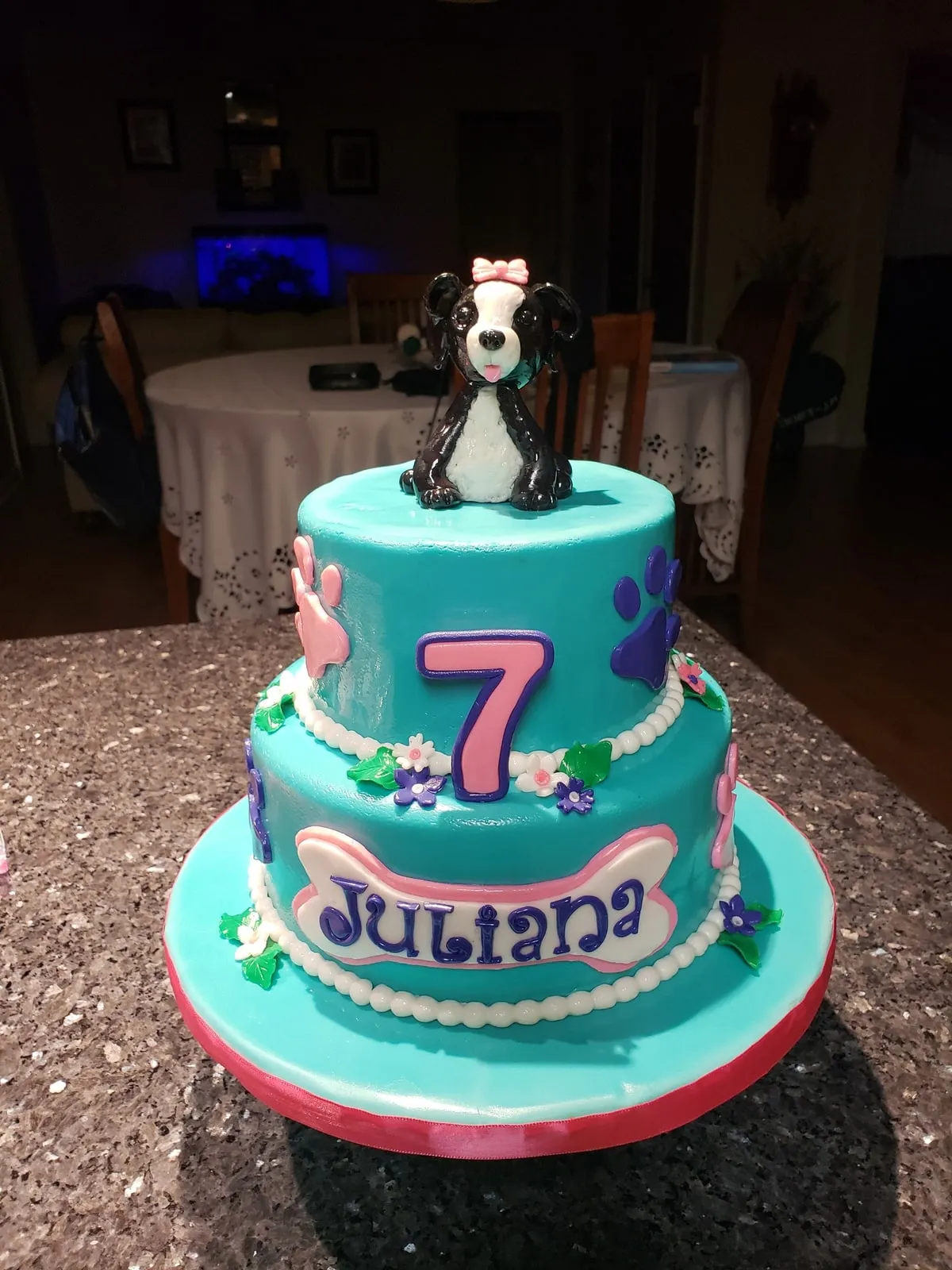 Turquoise two tier birthday cake with paw prints and a sculpted puppy topper