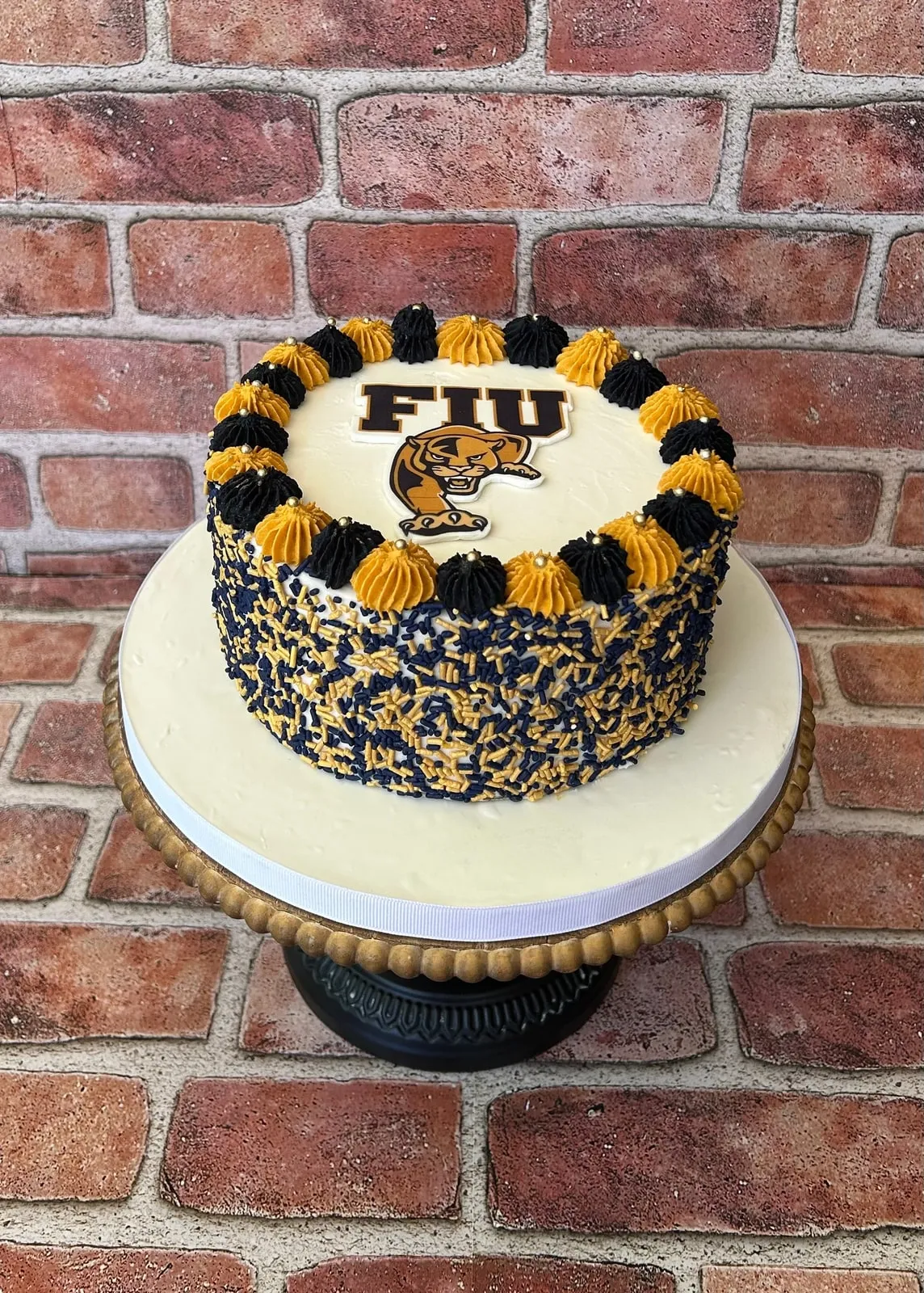 Graduation cake with a hand painted university crest and gold and navy piping