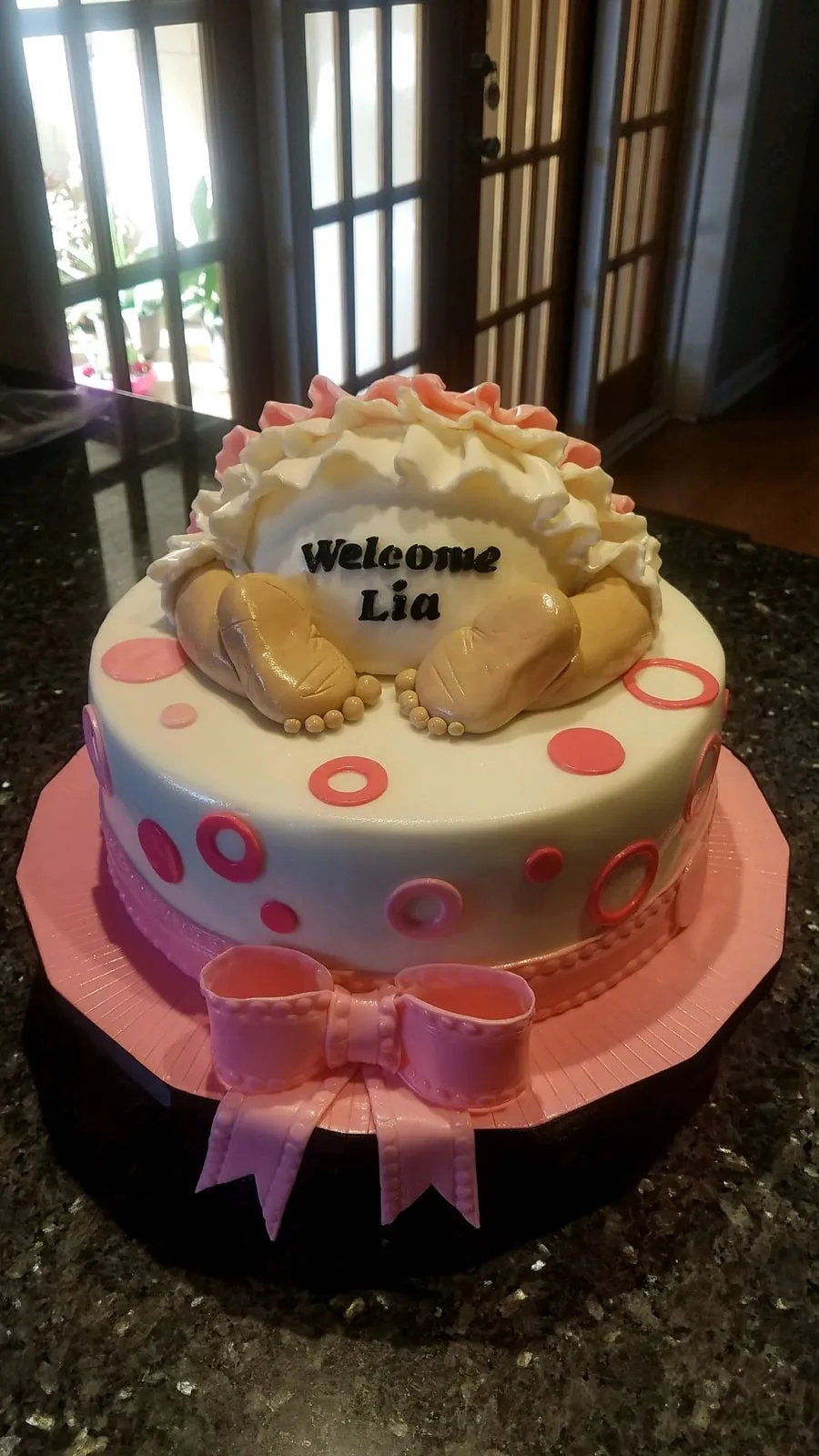 Pink and ivory two tier Welcome Baby cake with a sugar baby topper and bow